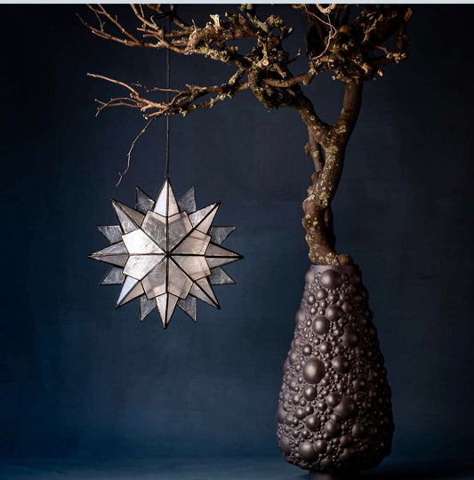 DIMAANO GRANDE Stern Schwarz
Stern Klatt Objects aus Capiz Muschel in Tiffany Technik. Kordel aus gewachster Baumwolle. Farbe: schwarz elektroplattiert